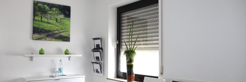 Wartebereich mit Zeitschriften, Wasser und Pflanze am Fenster